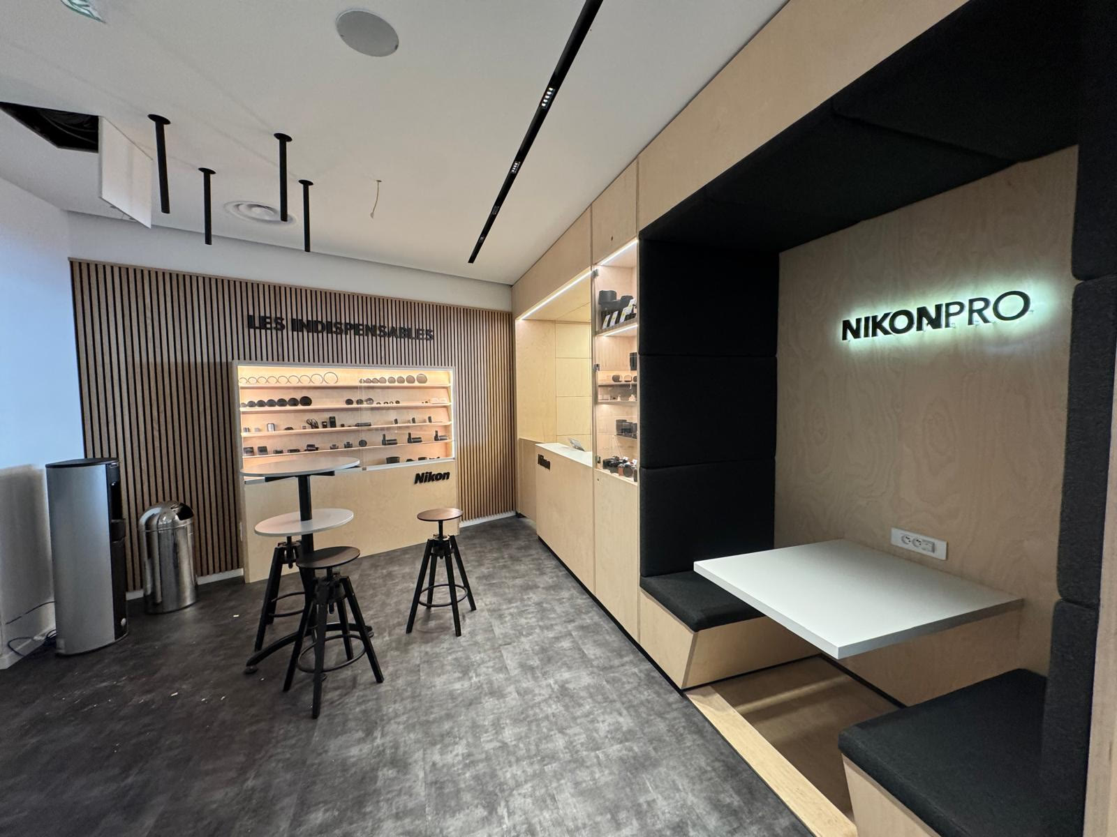 Nikon Pro retail interior: backlit NIKONPRO sign, timber slat display wall and an intimate seating nook.
