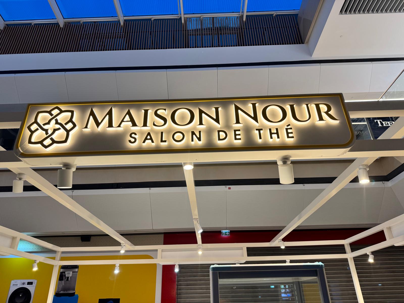 Illuminated gold Maison Nour tea-salon signage.